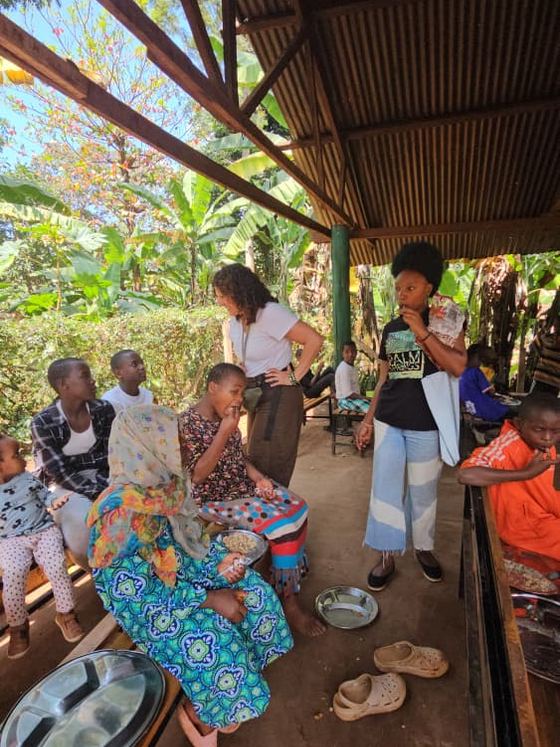 Niños y mujeres de la comunidad comparten la comida bajo el techado del patio.